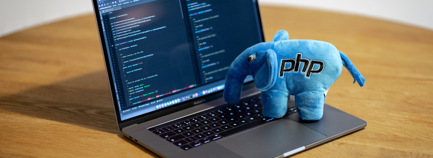 A laptop screen with showing a an IDE with an elephant soft toy on top of the keyboard
