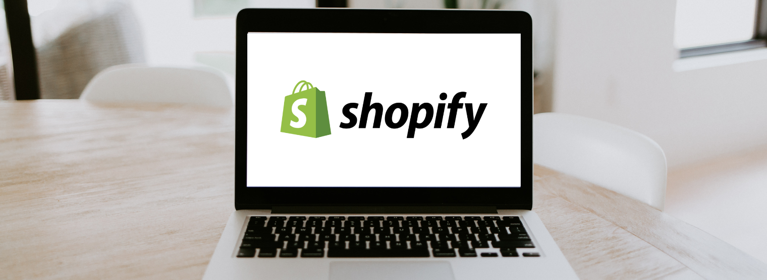 A laptop displaying the Shopify text and logo